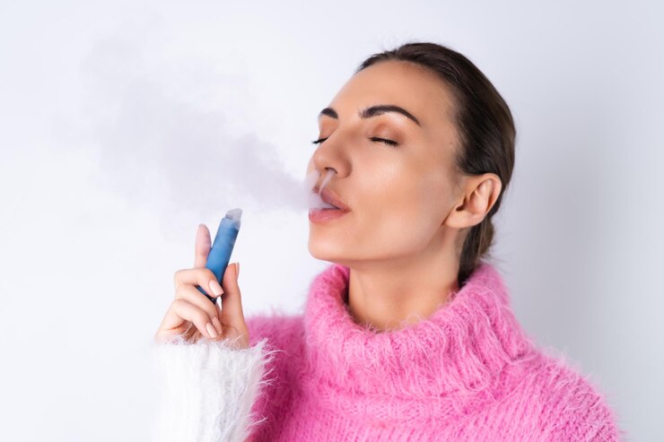 young cheerful girl bright colored sweater white background enjoys electronic disposable cigarette with her eyes closed smokes releases smoke 343596 8030